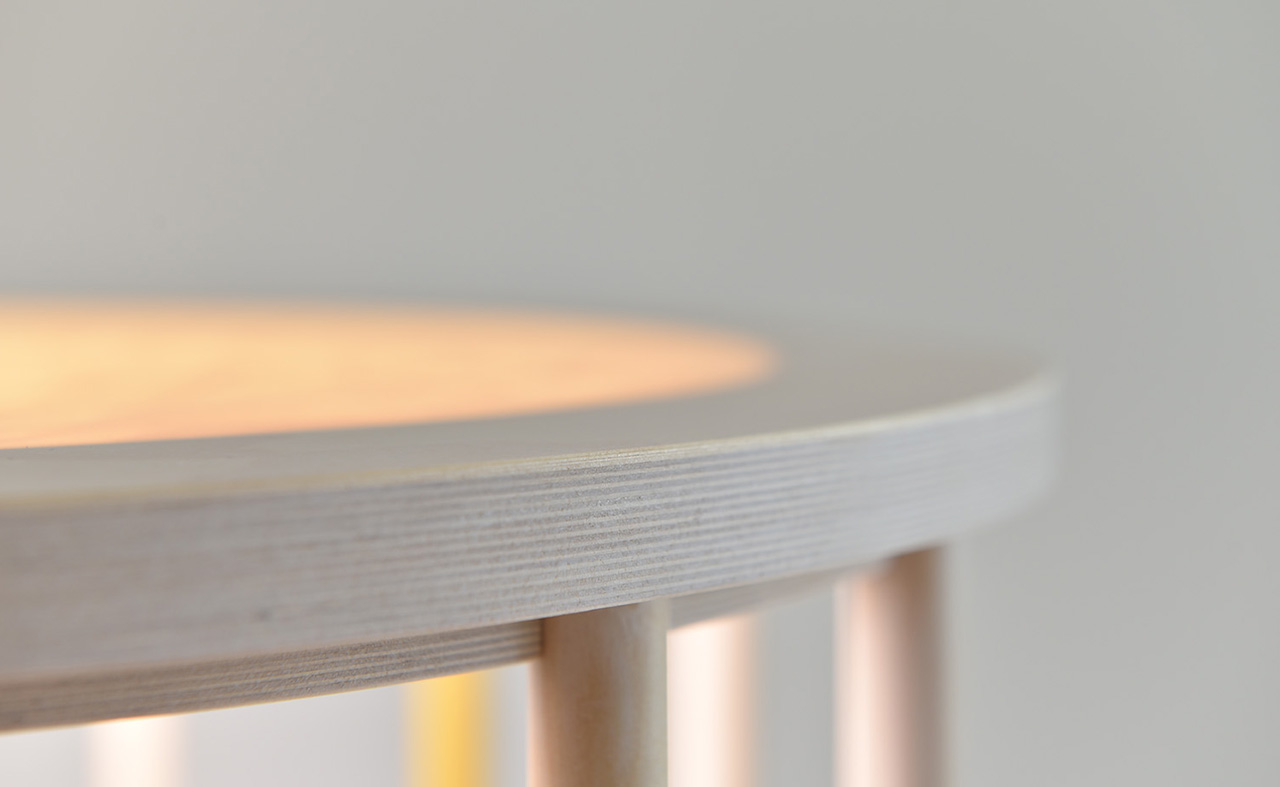 A detail of a round wood bedside light table.